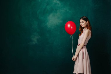 Kırmızı balonlu kadın yeşil arka planda tatil eğlencesi