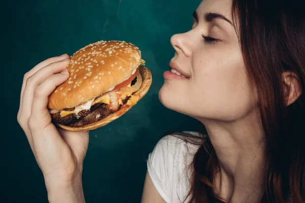 Mujer alegre con hamburguesa cerca de la cara snacking comida rápida —  Fotos de Stock