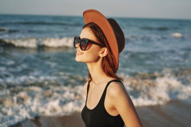 Kumsalda yürüyen bir kadın, tatil güneşinde seyahat ediyor.