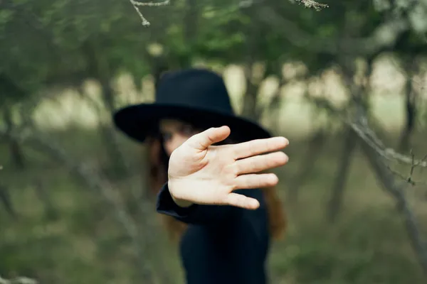 Mulher em um chapéu preto gesticulando com as mãos bruxa fantasia mágica — Fotografia de Stock