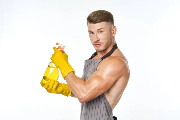 Homem bombeado em um avental com luvas de borracha detergentes — Fotografia de Stock