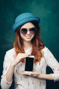 Mavi şapkalı şık bir kadın. Elinde telefon, iletişim teknolojisi var.