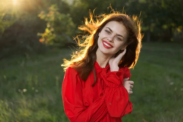 Glad kvinna i en röd klänning i ett fält utomhus frisk luft — Stockfoto