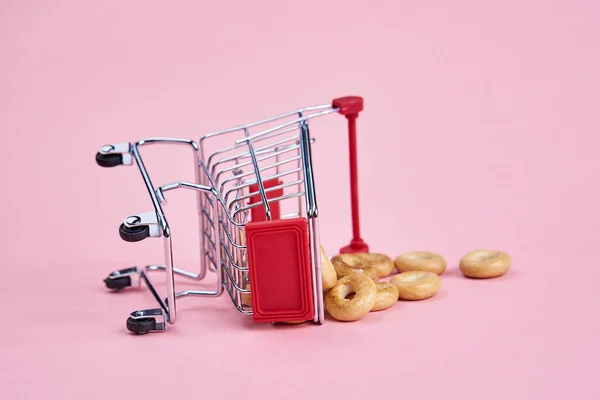 小さなショッピングカートスーパーマーケットショッピングピンクの背景 — ストック写真