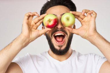 Elması beyaz tişörtlü, meyveli neşeli bir adam.