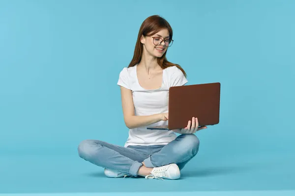 Mujer con portátil sentado en el piso de aprendizaje de la tecnología de los estudiantes fondo azul — Foto de Stock