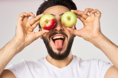Elması beyaz tişörtlü, meyveli neşeli bir adam.