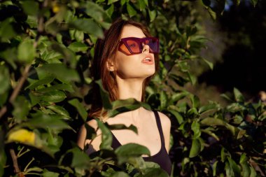 Yazın açık havada çekici bir kadın. Yeşil yapraklar moda.