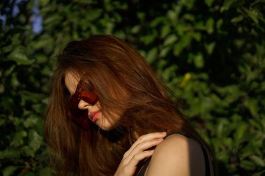 Güneş gözlüklü ve yeşil yapraklı şık bir kadın yaz egzotik