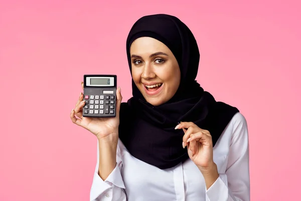 Muslim kvinna med miniräknare och ekonomi pengar rosa bakgrund — Stockfoto