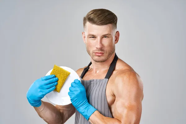 Een man in een schort die de afwas doet — Stockfoto