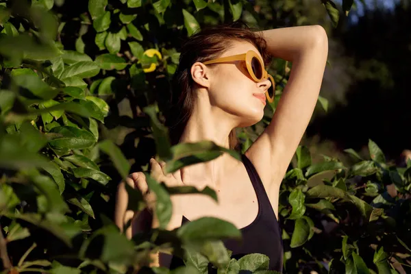 Csinos nő fekete fürdőruhában napszemüveg zöld levelek természet — Stock Fotó