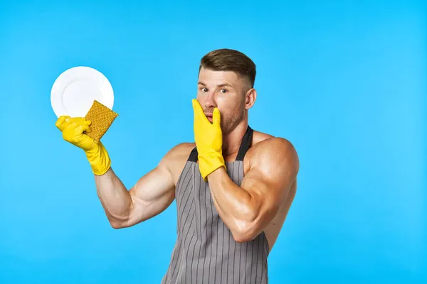 Un hombre con un cuerpo bombeado usando guantes de goma haciendo la tarea — Foto de Stock