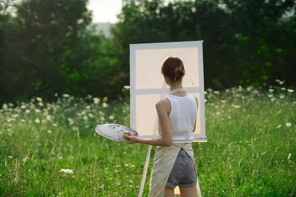 Женщина-художник на открытом воздухе с палитрой красок рисует картину — стоковое фото