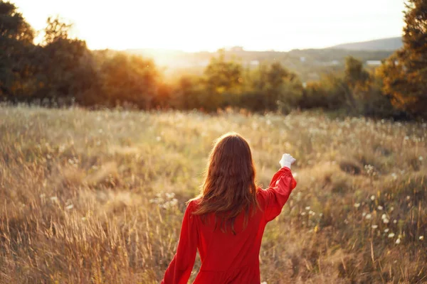 Mulher em vestido vermelho no campo com as mãos levantadas posando — Fotografia de Stock