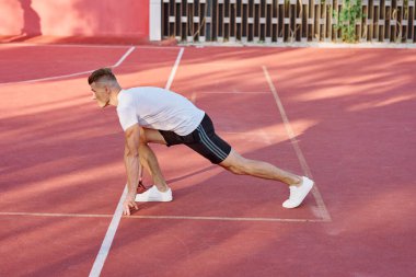 Atletik erkekler yazın spor sahasında egzersiz yapıyorlar.