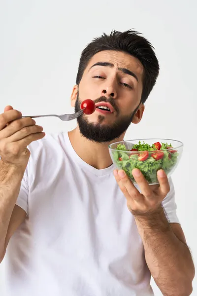 Homem alegre em uma camiseta branca com um prato de verde claro e uma refeição saudável — Fotografia de Stock