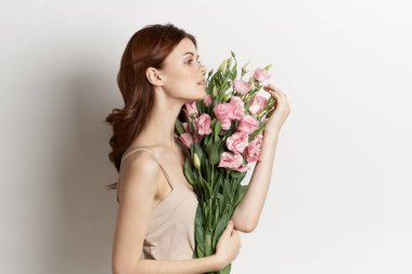 Çiçeklere makyaj arkaplanı pozu veren güzel kadın.