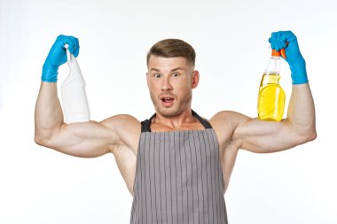 Önlük giyip temizlik yapan kaslı bir adam.