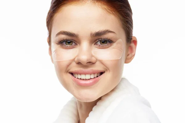 Mulher de roupão branco posando divertidas manchas de cuidados da pele no rosto — Fotografia de Stock