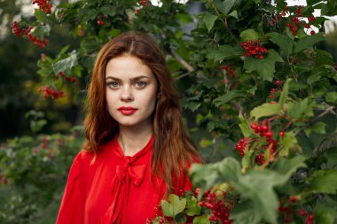 Kırmızı elbiseli güzel bir kadın yeşil yapraklı doğal yaz mevsimi.