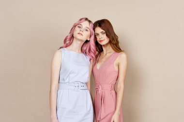 İki kız arkadaş yan yana durmuş, moda zevkini sergiliyorlar.