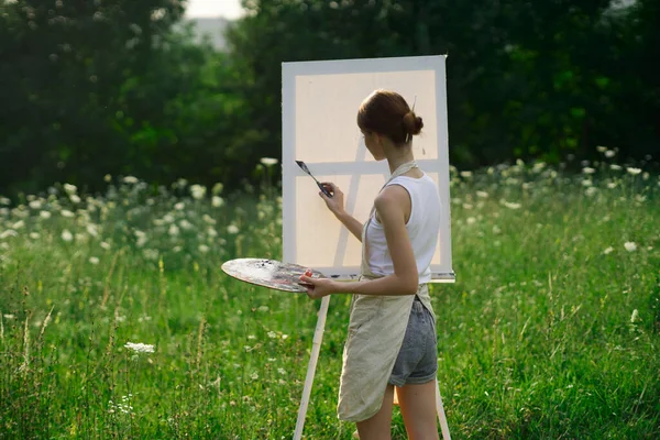 Artista mulher ao ar livre com paleta de tintas pinta um quadro — Fotografia de Stock