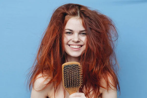 Kvinna med bar skuldror rufsigt rött hår kam blå bakgrund — Stockfoto