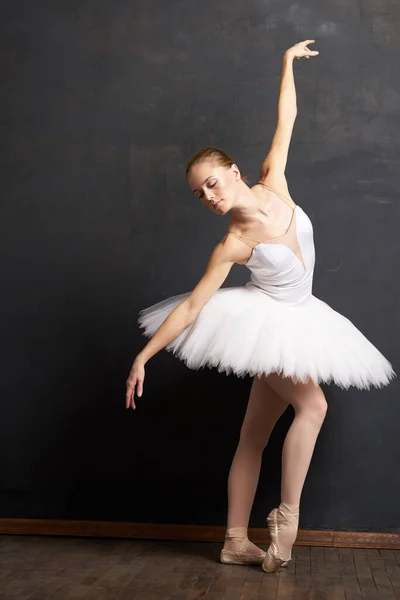 Mulher bailarina em um branco tutu dança posando desempenho fundo escuro — Fotografia de Stock