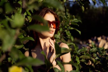Yazın açık havada çekici bir kadın. Yeşil yapraklar moda.