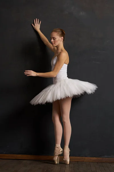 Mulher bailarina em um branco tutu dança posando desempenho fundo escuro — Fotografia de Stock