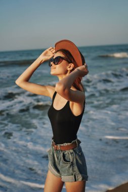 Kumsalda yürüyen bir kadın, tatil güneşinde seyahat ediyor.