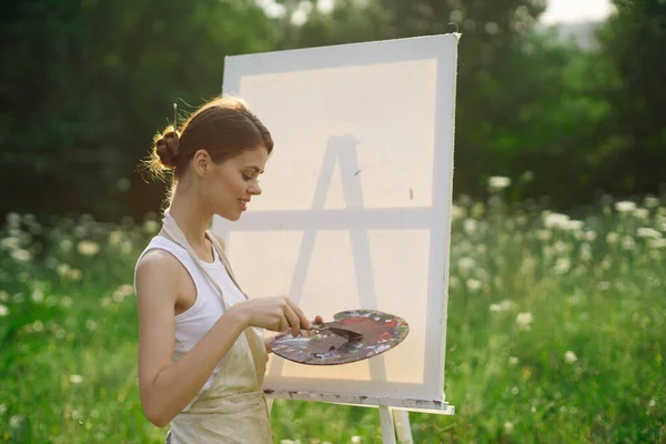 Kadın ressam açık havada palet boyayıp manzara resmi yapıyor. — Stok fotoğraf