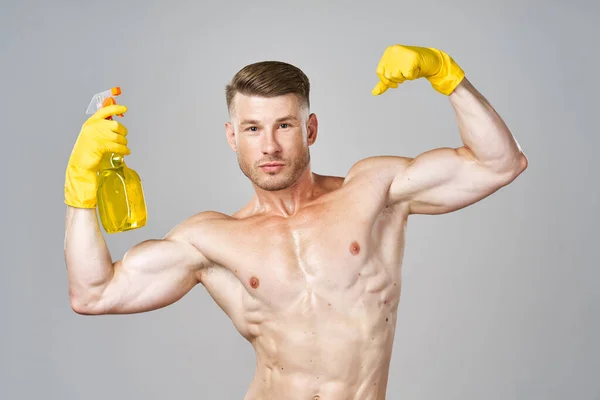 Férfi sárga gumikesztyűben pumpált izmokkal mosószer tisztítás — Stock Fotó
