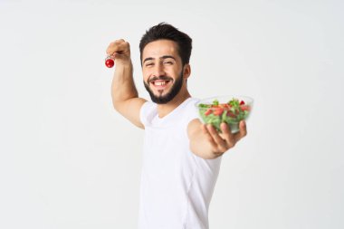 Beyaz tişörtlü neşeli adam salata sebzeli bir tabak diyet