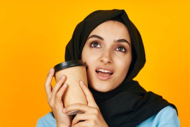 Stüdyo yaşam tarzı pozu veren sıcak bir içecek içen güzel bir kadın.