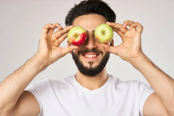 Vrolijke man met appels in zijn handen in een wit t-shirt vruchten — Stockfoto