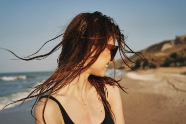 Siyah mayo giymiş güzel bir kadın bronzlaştırıcı tropiklerde poz veriyor