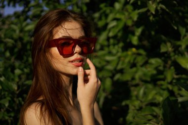 Yeşil yaprakların arkasında poz veren çekici bir kadın.