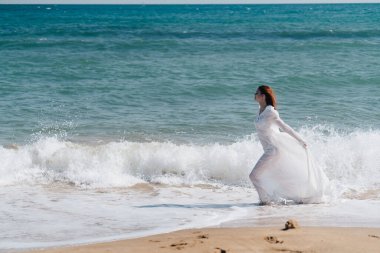 Güzel kadın elbisesi sahilde özgürce yürüyor. Temiz hava.