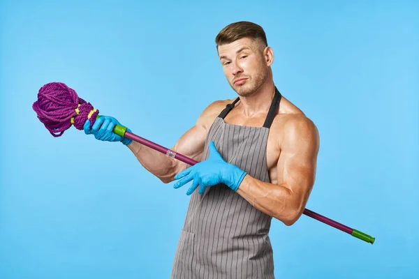 Een man in een schort met een dweil in zijn handen schoonmaakdienst — Stockfoto