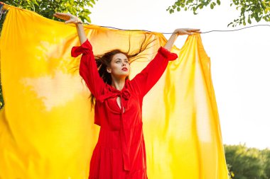 Sarı arka plan pozu veren kırmızı elbiseli çekici kadın.