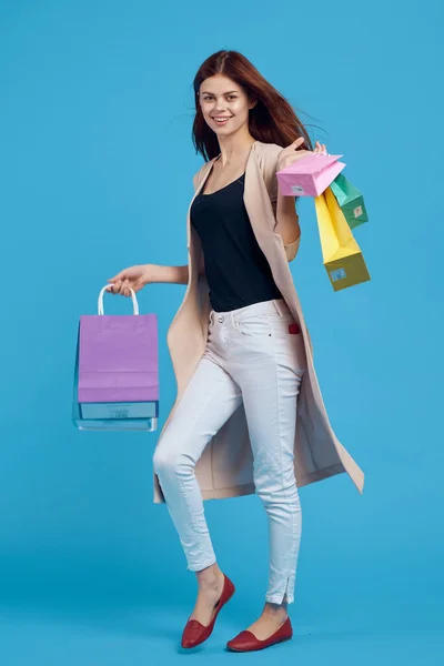 Mujer alegre con bolsas multicolores posando fondo azul —  Fotos de Stock