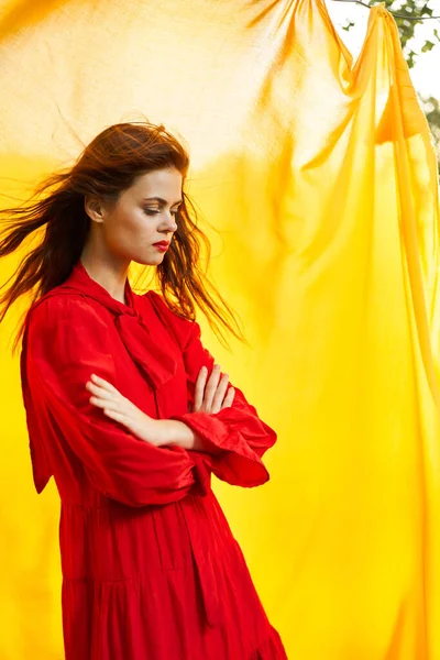 Jolie femme en robe rouge nature tissu jaune sur fond — Photo