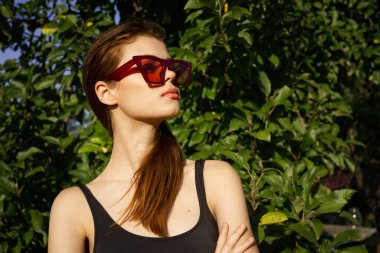 Yeşil yaprakların arkasında poz veren çekici bir kadın.