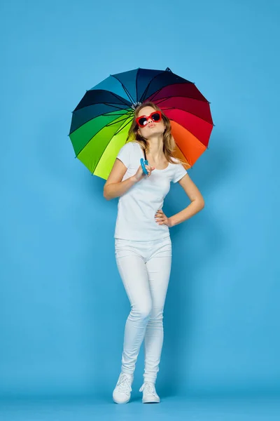 Femme à la mode avec des couleurs parapluie arc-en-ciel posant fond bleu — Photo