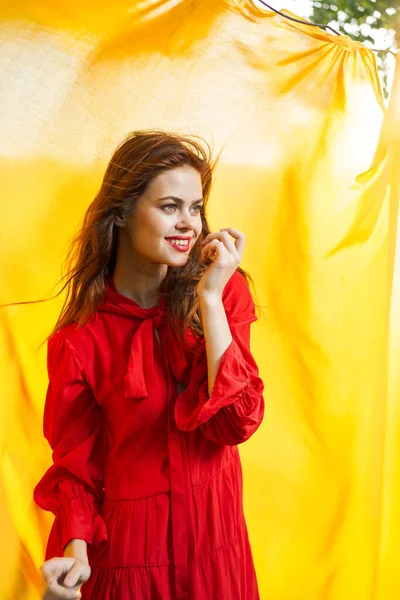 Mulheres perto de tecido amarelo na natureza na moda vestido vermelho — Fotografia de Stock