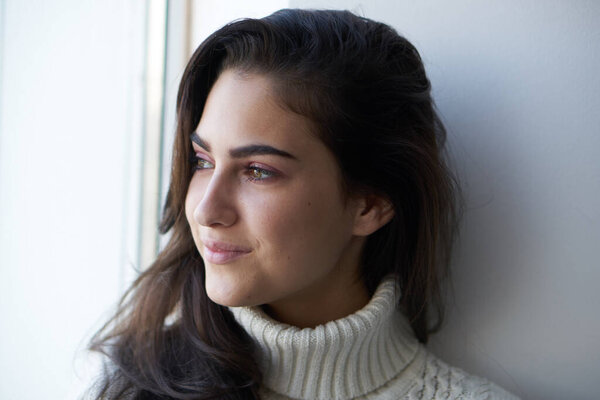 красивая женщина в белом свитере возле окна