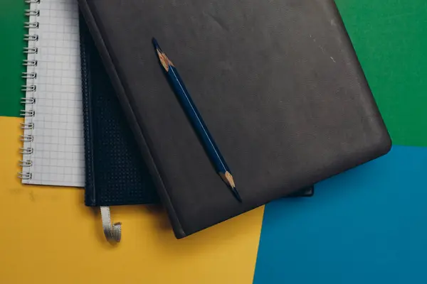 Fekete notepad ceruza színes háttér irodai kellékek — Stock Fotó