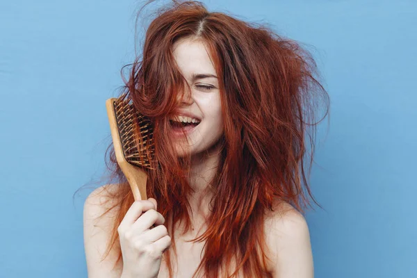 Mulher com ombros nus tousled cabelo vermelho pente azul fundo — Fotografia de Stock